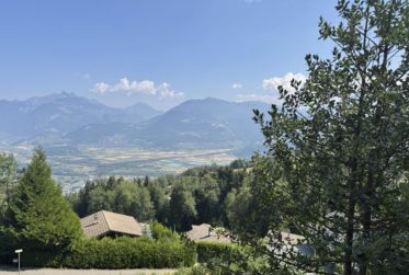 Chalet en rondins d’épicéa dans un écrin de verdure, avec vue sur la plaine du Rhône